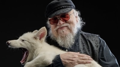 George RR MArtin poses with one of the three dire wolf pups George RR MArtin poses with one of the three dire wolf pups