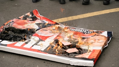 A poster with images of Pete Hegseth, U.S. President Donald Trump, and Panama's President Jose Raul Mulino was set ablaze during a protest against Hegseth, (REUTERS)