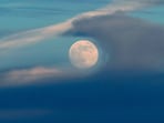 A full moon rises above the clouds at sunset in Lisbon, Saturday, Dec 14, 2024. 