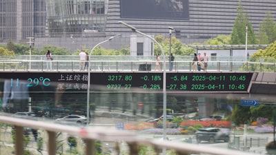 An electronic board shows Shanghai and Shenzhen stock indices as people walk on a pedestrian bridge at the Lujiazui financial district in Shanghai, China April 11, 2025. (Go Nakamura/Reuters)