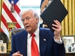 President Donald Trump holds an executive order in the Oval Office of the White House, in Washington. President Donald Trump holds an executive order in the Oval Office of the White House, in Washington.