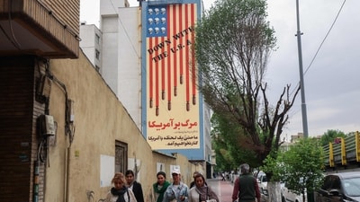 People walk along Tehran's Karim Khan Zand Avenue past a building with a landmark anti-US mural with the slogan "Down with the USA" and skulls replacing the stars on the US flag, on April 12, 2025. Iran's top diplomat arrived in Oman on April 12 and began laying the groundwork for high-stakes nuclear talks with the United States that are unfolding under the threat of military action. (AFP) People walk along Tehran's Karim Khan Zand Avenue past a building with a landmark anti-US mural with the slogan "Down with the USA" and skulls replacing the stars on the US flag, on April 12, 2025. Iran's top diplomat arrived in Oman on April 12 and began laying the groundwork for high-stakes nuclear talks with the United States that are unfolding under the threat of military action. (AFP)