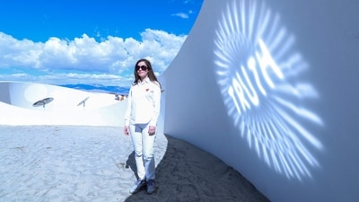 French-American artist Sarah Meyohas poses in front of her piece “Truth Arrives in Slanted Beams,”(Photo by Valerie MACON / AFP) (AFP) French-American artist Sarah Meyohas poses in front of her piece “Truth Arrives in Slanted Beams,”(Photo by Valerie MACON / AFP) (AFP)