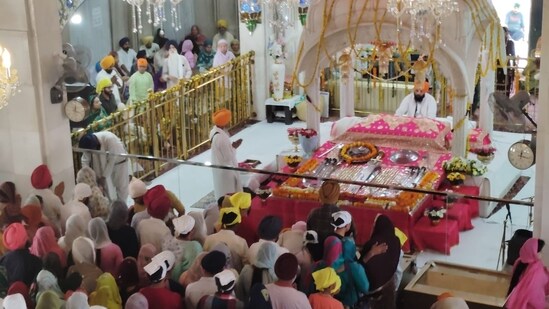 At the gurudwara's sacrosanctum, devotees bow and pray to Guru Granth Sahib.