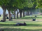 People resting under tree shade at Kartavya Path lawns in the afternoon in Delhi on Saturday, April 12.