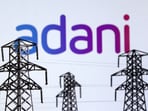 Electric power transmission pylon miniatures and Adani Green Energy logo are seen in this illustration taken, December 9, 2022.