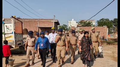 Police and administration officials conducting a flag march in Etah’s Mohanpura village on Tuesday. (HT photo)