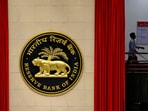 A worker walks past the logo of Reserve Bank of India (RBI) inside its office in New Delhi, India.