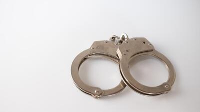 A high angle shot of metal handcuffs isolated on a white background A high angle shot of metal handcuffs isolated on a white background