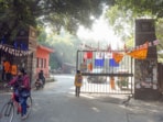 A woman passes on a cycle at the JNU gate. The notices warn that “any future complaints or violations will result in your immediate eviction from the hostel without prior notice”.