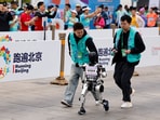 Engineers run with the humanoid robot "Noetix N2" as it participates along with human runners in the E-Town Half Marathon & Humanoid Robot Half Marathon in Beijing, China April, 19 2025.