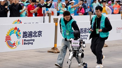 Engineers run with the humanoid robot "Noetix N2" as it participates along with human runners in the E-Town Half Marathon & Humanoid Robot Half Marathon in Beijing, China April, 19 2025. (REUTERS)