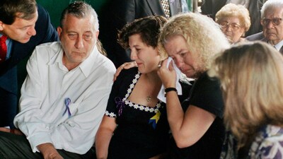 Aren Almon, center, whose daughter Baylee became a national symbol in an iconic photo of a firefighter holding her lifeless body following the bombing of the federal building in Oklahoma City, is comforted by her father Tommy Almon and mother Debbie Almon, during a funeral service for Baylee at Arlington Memorial Park Cemetery in Oklahoma City, April 24, 1995. (AP Photo/Pat Sullivan, File) (AP)