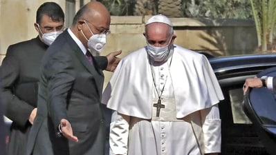 Pope Francis is welcomed by then-Iraqi President Barham Saleh at the presidential palace in Baghdad on March 5, 2021, on the first papal visit to Iraq. SABAH ARAR/AFP/GETTY 
