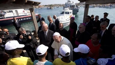 Pope Francis speaks to migrants, wearing white caps, during his visit to the island of Lampedusa, southern Italy, on July 8, 2013. Alessandra Tarantino/AP Photos 