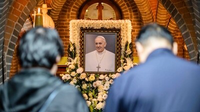 People pay their respects in front of a portrait of late Pope Francis displayed inside Myeongdong Cathedral in Seoul Tuesday, April 22. (AP)