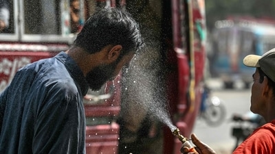 A volunteer of the Edhi Foundation sprays water on a passerby's face to cool off on a hot summer day along a road amid the ongoing heatwave in Karachi on April 21, 2025. (Photo by Asif HASSAN / AFP) (AFP)