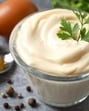 Bowl with mayonnaise and ingredients for cooking on gray background (Shutterstock)