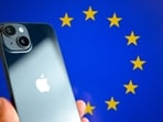 This photograph shows a hand-held smartphone with the Apple company logo and the European Union logo in the background, This photograph shows a hand-held smartphone with the Apple company logo and the European Union logo in the background,