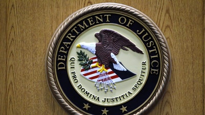A Department of Justice logo is shown on a podium during a news conference. (AP) A Department of Justice logo is shown on a podium during a news conference. (AP)