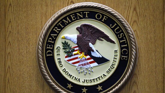 A Department of Justice logo is shown on a podium during a news conference. (AP)