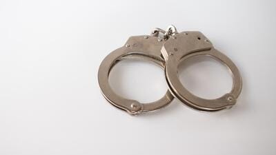 A high angle shot of metal handcuffs isolated on a white background A high angle shot of metal handcuffs isolated on a white background