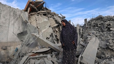 A woman stands amid the rubble of a building destroyed in an Israeli strike at the Bureij refugee camp in the central Gaza Strip (AFP)