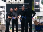 Members of the Vancouver Police forensics team examine a victim's phone while investigating the scene where a vehicle drove into a crowd Saturday killing multiple people at a street festival, in Vancouver, British Columbia, Sunday, April 27, 2025. (The Canadian Press via AP/PTI)(AP04_28_2025_000033B)