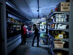 A worker assists a customer with a torch at a supermarket during a power outage which hit large parts of Spain, in Barcelona, Spain April 28, 2025.