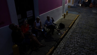 People sit on the sidewalk of a dark street after Puerto Rico was hit with a massive power outage where energy plants across the island unexpectedly shut down, in San Juan, Puerto Rico April 16, 2025.  REUTERS/Ricardo Arduengo (REUTERS)