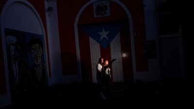 A couple take a selfie in front of a Puerto Rican flag after the country was hit with a massive power outage where energy plants across the island unexpectedly shut down, in San Juan, Puerto Rico April 16, 2025.  REUTERS/Ricardo Arduengo     TPX IMAGES OF THE DAY (REUTERS)