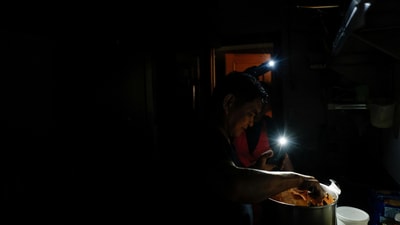 A cook from "La Cocinona" home-made take out food restaurant works in a dark kitchen with the aid of phone flashlights, during a power outage in Madrid, Spain, April 28, 2025. REUTERS/Susana Vera     TPX IMAGES OF THE DAY (REUTERS)