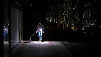 TOPSHOT - A woman uses her phone's torch while she walks her dog as the street lies in complete darkness during a massive power cut affecting the entire Iberian peninsula and the south of France, in Vigo on April 28, 2025. Spanish Prime Minister Pedro Sanchez said today authorities were not ruling out any cause for the widespread blackout across the Iberian pensisula. "All potential causes are being analysed, I insist, without ruling out any hypothesis, any possibility," Sanchez told a press conference, 11 hours after Spain and Portugal were plunged into darkness for reasons that had yet to be determined. (Photo by MIGUEL RIOPA / AFP) (AFP) TOPSHOT - A woman uses her phone's torch while she walks her dog as the street lies in complete darkness during a massive power cut affecting the entire Iberian peninsula and the south of France, in Vigo on April 28, 2025. Spanish Prime Minister Pedro Sanchez said today authorities were not ruling out any cause for the widespread blackout across the Iberian pensisula. "All potential causes are being analysed, I insist, without ruling out any hypothesis, any possibility," Sanchez told a press conference, 11 hours after Spain and Portugal were plunged into darkness for reasons that had yet to be determined. (Photo by MIGUEL RIOPA / AFP) (AFP)