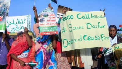 People lift national flags and placards during a rally called for by Sudan's Popular Front for Liberation and Justice in Port Sudan to denounce the siege imposed by the paramilitary Rapid Support Forces (RSF) on El-Fasher city. (AFP)