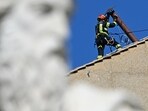 A worker installs the chimney on the roof of the Sistine Chapel, with the statue of Saint Paul in the foreground, in The Vatican, on May 2, 2025.