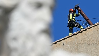 A worker installs the chimney on the roof of the Sistine Chapel, with the statue of Saint Paul in the foreground, in The Vatican, on May 2, 2025. (AFP)