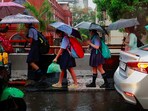 School children use umbrellas to cover themselves from the rain as they walk to school, in New Delhi. 