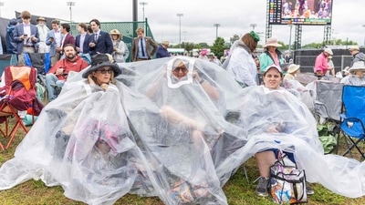 Guests huddle under a large plastic bag for cover as they watch the races ahead of the 151st running of the Kentucky Derby at Churchill Downs on May 3, 2025, in Louisville, Kentucky. (Photo by LEANDRO LOZADA / AFP) (AFP) Guests huddle under a large plastic bag for cover as they watch the races ahead of the 151st running of the Kentucky Derby at Churchill Downs on May 3, 2025, in Louisville, Kentucky. (Photo by LEANDRO LOZADA / AFP) (AFP)