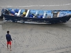 A Del Mar lifeguard looks over a capsized boat on the beach Monday at Torrey Pines State beach in San Diego, California.