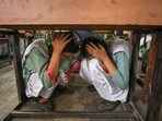 School students crouch under a desk during a drill conducted as part of a nationwide civil defence exercise, in Ghaziabad on Wednesday. School students crouch under a desk during a drill conducted as part of a nationwide civil defence exercise, in Ghaziabad on Wednesday.