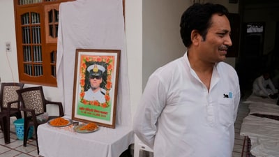 Sunil Swami stands next to a framed portrait of his son-in-law and Indian naval officer Vinay Narwal, who was killed by terrorists in  Pahalgam. (AP)