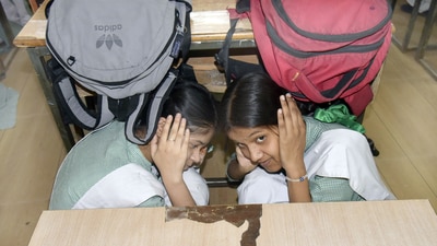 School students take shelter under a bench during a mock drill at Nagar Nigam Balika Inter College in Ghaziabad. (Sakib Ali/HT)
