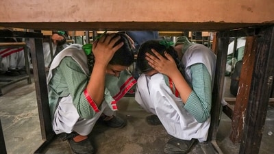 School students crouch under a desk during a drill conducted as part of a nationwide civil defence exercise, in Ghaziabad on Wednesday. (PTI) School students crouch under a desk during a drill conducted as part of a nationwide civil defence exercise, in Ghaziabad on Wednesday. (PTI)