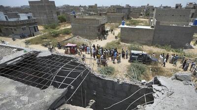A big hole is seen on a rooftop of a structure suspected to have been damaged in Indian drone attack as residents gather near a cordoned off site where Pakistan's air defence system shot down a suspected Indian drone in Karachi on May 8 (AP) A big hole is seen on a rooftop of a structure suspected to have been damaged in Indian drone attack as residents gather near a cordoned off site where Pakistan's air defence system shot down a suspected Indian drone in Karachi on May 8 (AP)