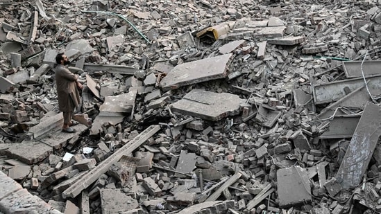 Locals stand on the debris of destroyed structures in Muridke about 30 kilometres from Lahore, on May 7 (AFP)