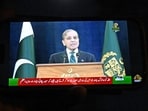 A resident watches his smartphone as Pakistan's Prime Minister Shehbaz Sharif addresses the nation in Islamabad on May 10, 2025. Pakistan and India agreed on May 10 to a full and immediate ceasefire after days of military clashes.