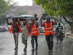 Workers huddle together under a plastic sheet during rainfall, in New Delhi. Workers huddle together under a plastic sheet during rainfall, in New Delhi.
