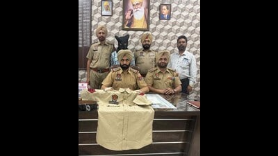 A police officer shows the seized uniform. (HT Photo) A police officer shows the seized uniform. (HT Photo)