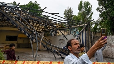 A man takes a picture in front of the wreckage of a restaurant's shade outside the Rawalpindi cricket stadium after an alleged drone was shot down in Rawalpindi on May 8. (AFP)