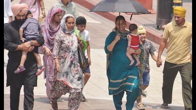 A woman shields her child from the scorching heat under an umbrella in Amritsar on Thursday. (Sameer Sehgal/HT)